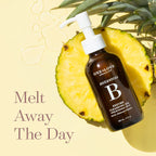 A bottle of One+Love Organics Botanical Enzyme Cleansing Oil lies on a sliced pineapple