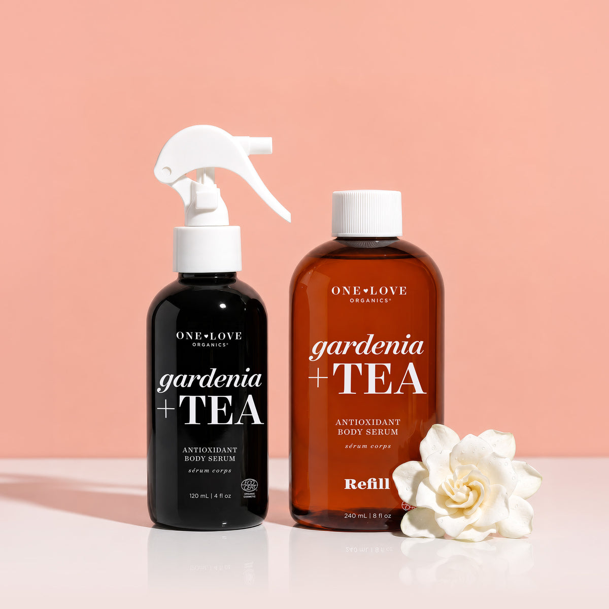 Two bottles of One Love Organics gardenia tea products on a peach background with a white flower.