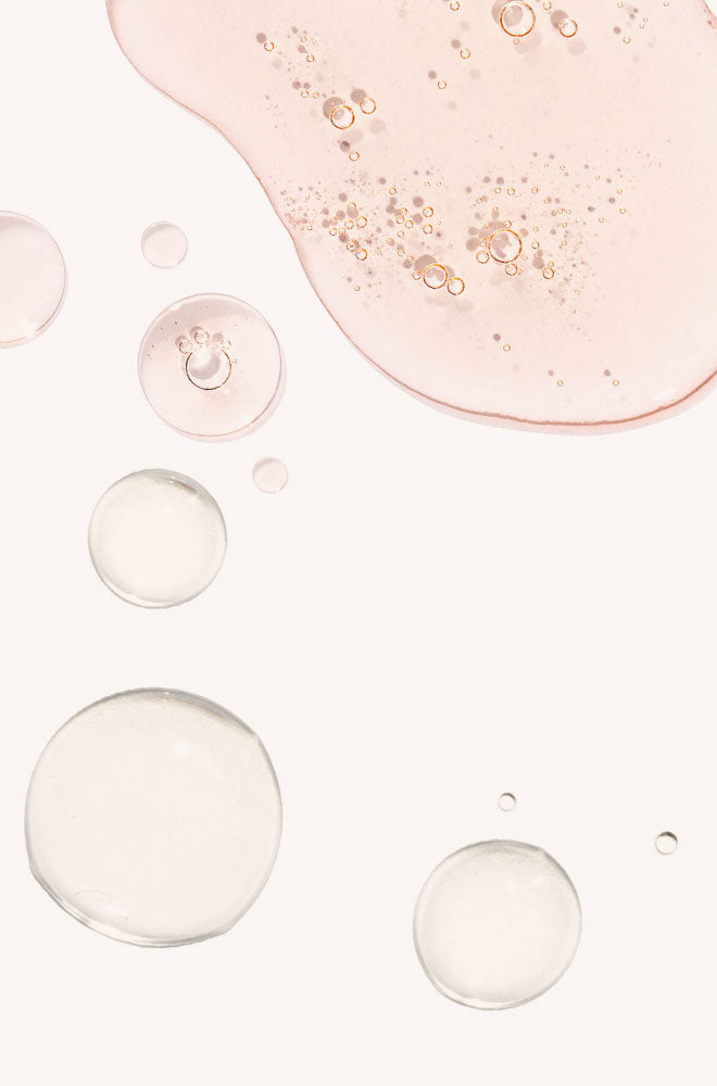 A close-up abstract shot of a pale pink translucent liquid 