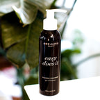 A bottle of One Love Beauty Easy Does It Foaming Cleanser with a white pump dispenser on a white surface