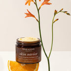 A jar of One Love Organics Skin Savior Multi-Tasking Wonder Balm with a white cream visible at the top