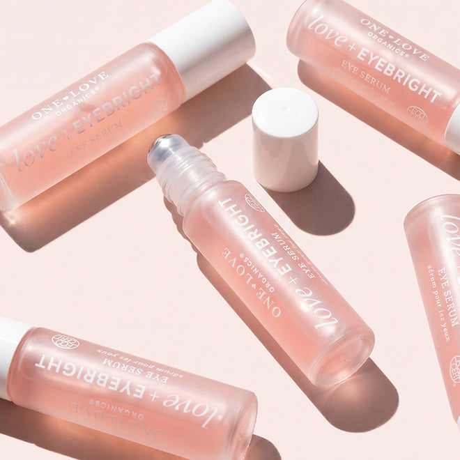 Several pink eyebright roll-on eye serum bottles with white caps 