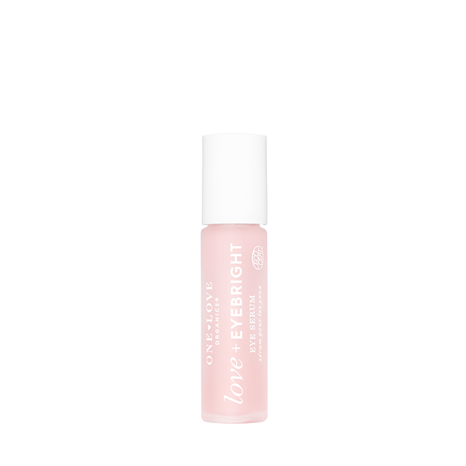 A bottle of One Love Organics Love + Eyebright Eye Serum in a soft pink shade with a white cap, centered on a plain white background.