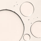 Abstract close-up of translucent circular droplets and large liquid bubbles on a warm off-white background.
